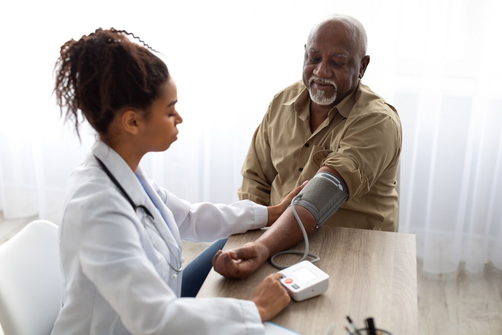 A doctor taking an older man's blood pressure.