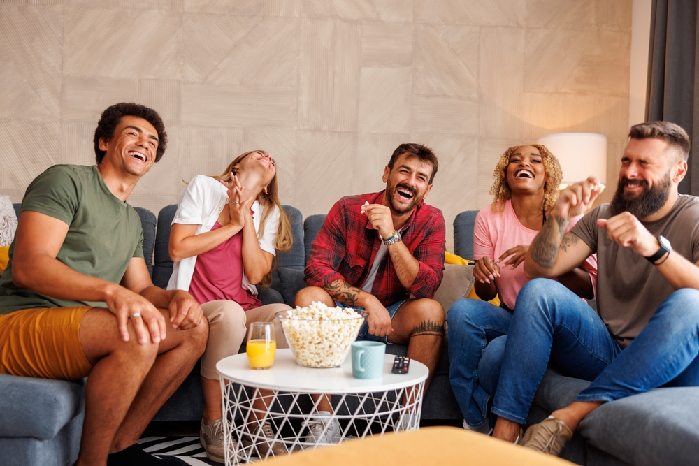 A group of friends watching a movie together and laughing.