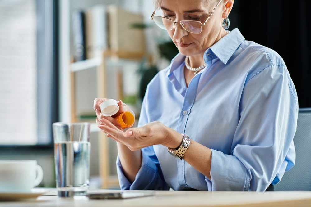 A woman looking at a pill container.