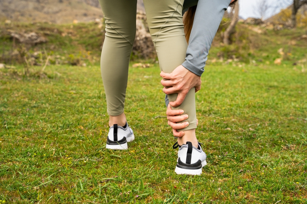 A woman holding her calf in pain.
