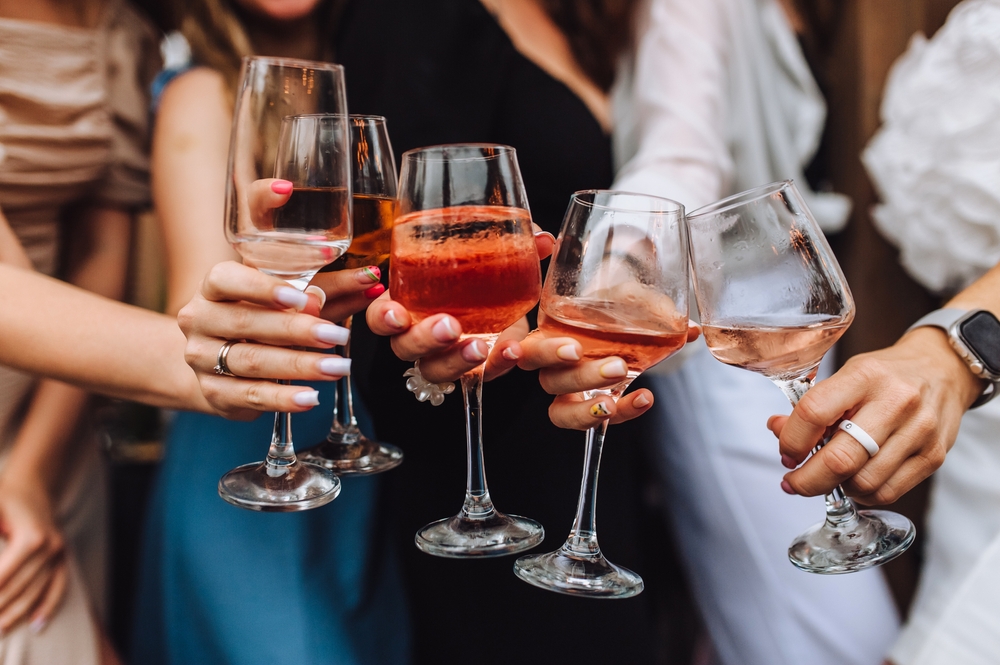 Close-up of hands holding glasses of wine at a table